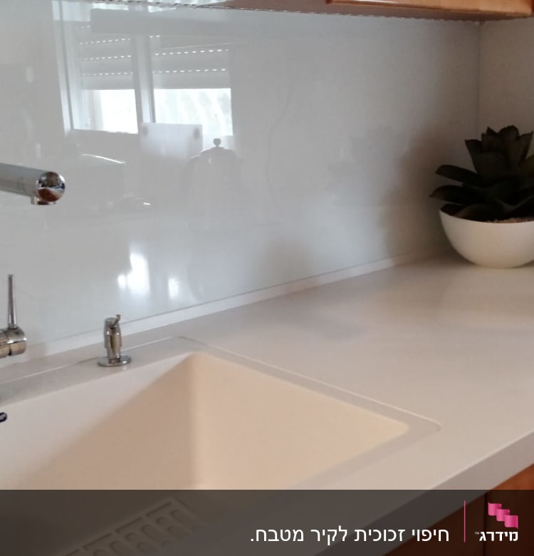 משטח זכוכית לבן במטבח עם ברזים